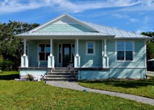 light blue single family home with green grass and trimmed walkway